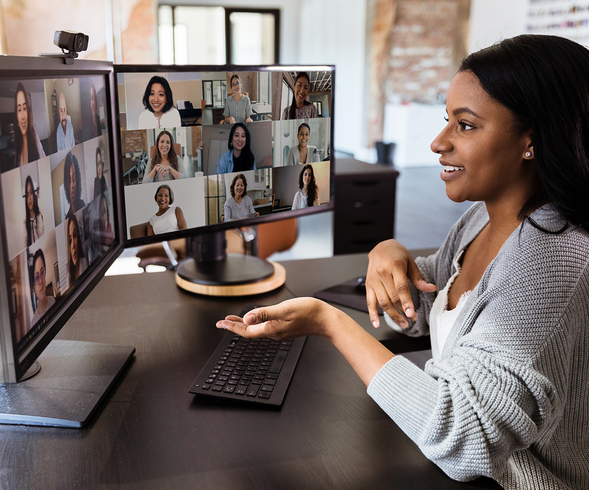 Photo of a woman seated in front of two computer monitors, participating in an online CZI capacity building training session with multiple attendees.