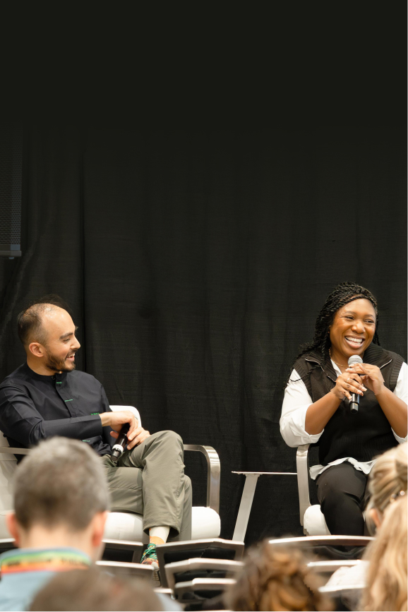 Playlab CEO Yusuf Ahmad and Aneka Bruce smile during a panel at SXSW EDU 2025. They are sitting in front of a black curtain.