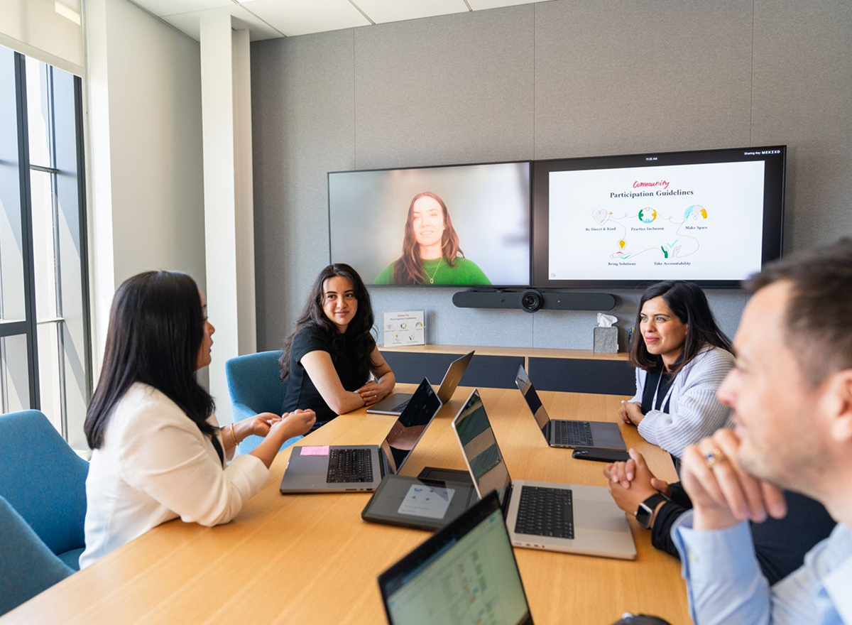 a group sits at a conference table during a virtual conference call